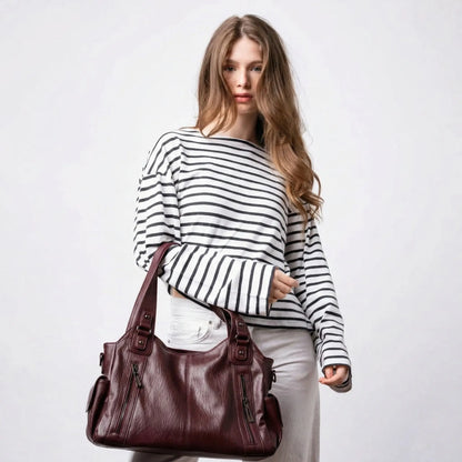 Woman carrying Malibu Bag wine red leather duffel bag street style
